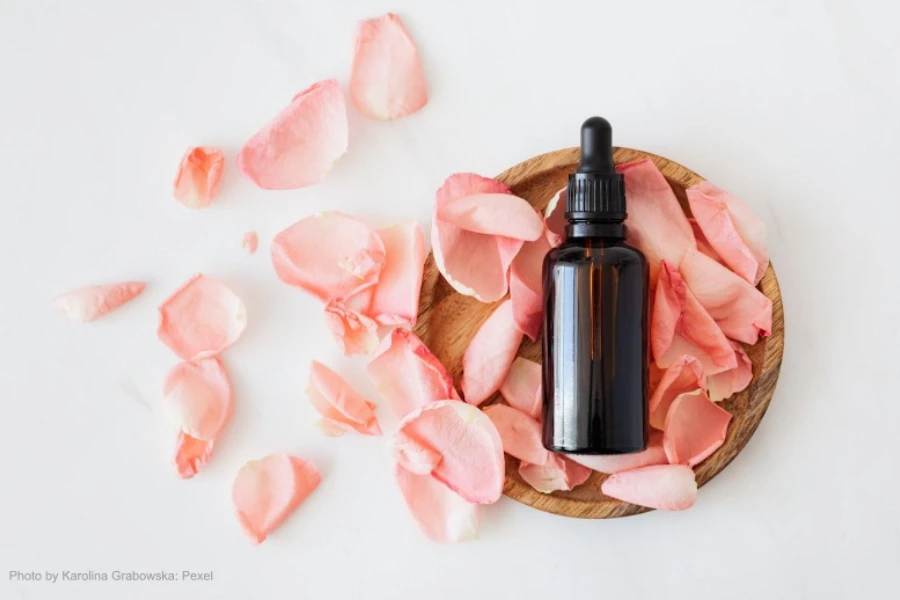 Composition of a cosmetic bottle with pink rose petals