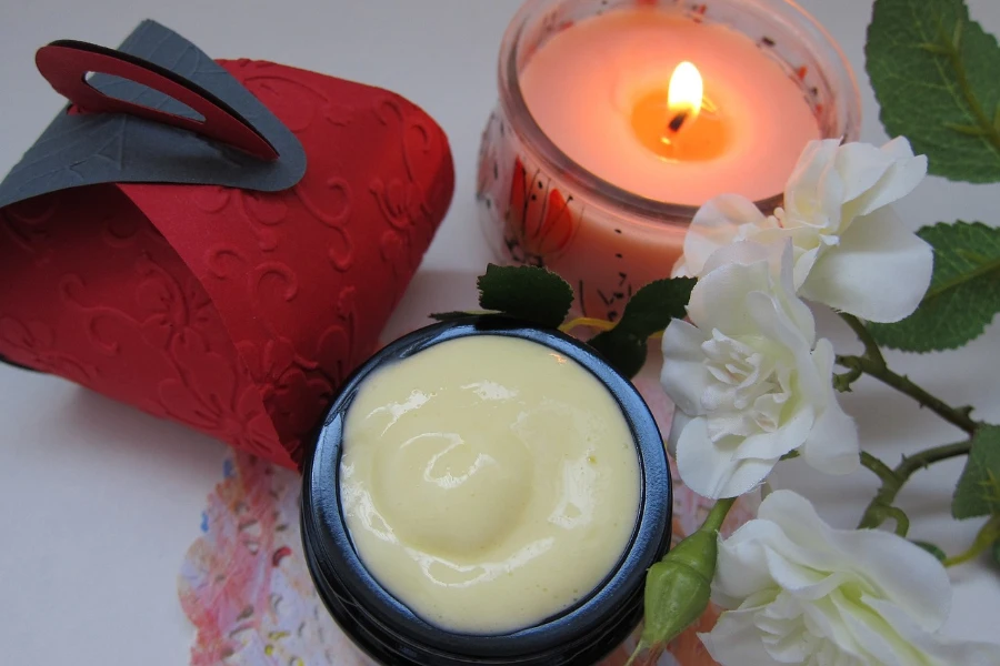Cream and candle next to flowers