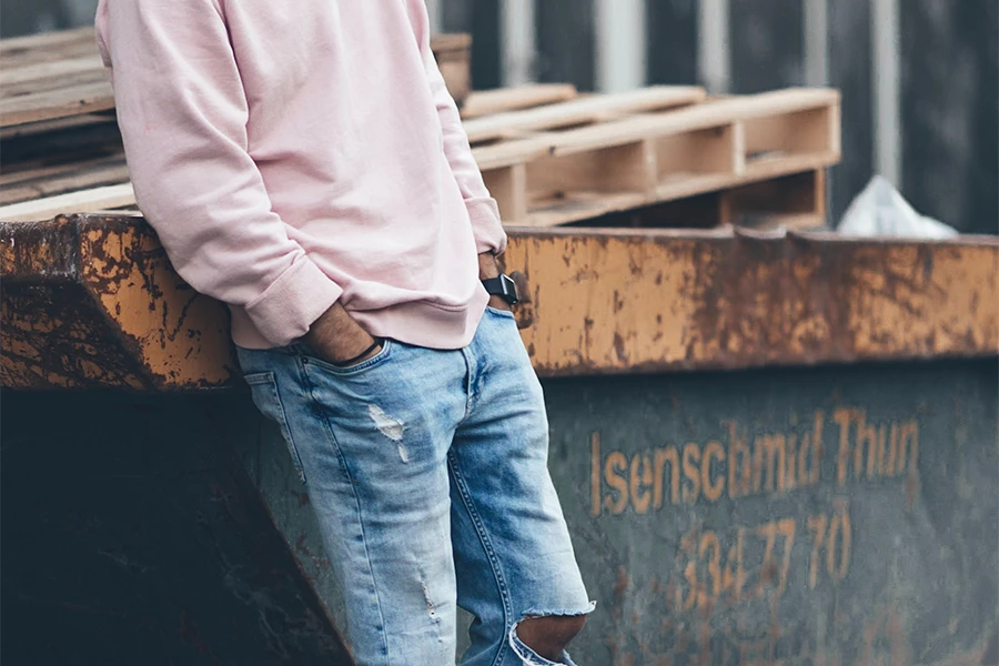 Guy wearing a pink cardigan with ripped jeans