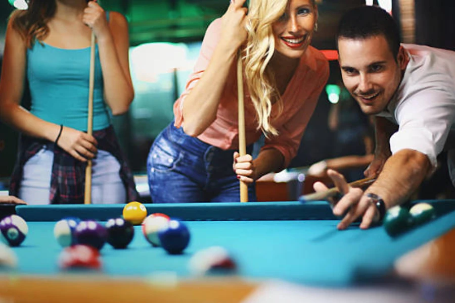 Man hitting a ball on the billiards table with group