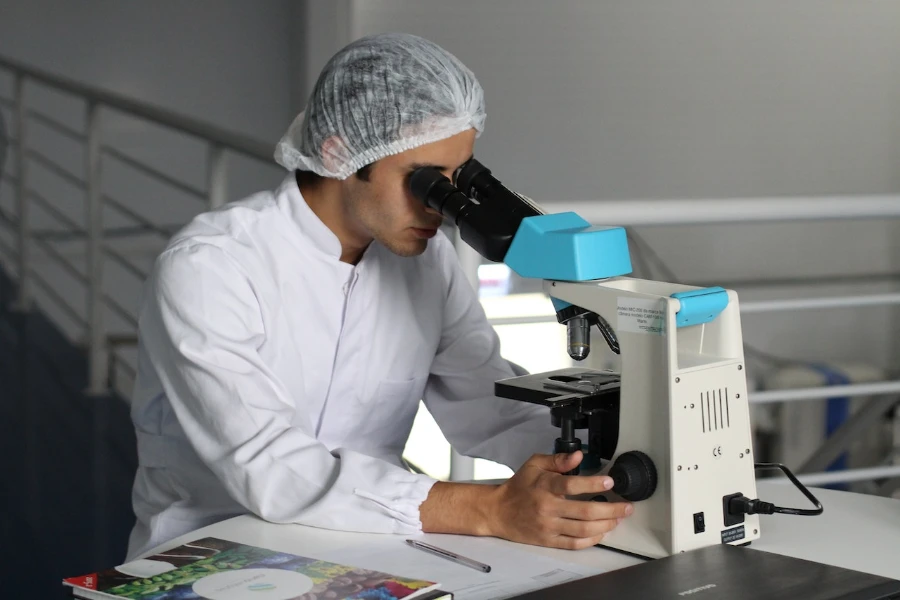 Homme en laboratoire regardant à travers un microscope