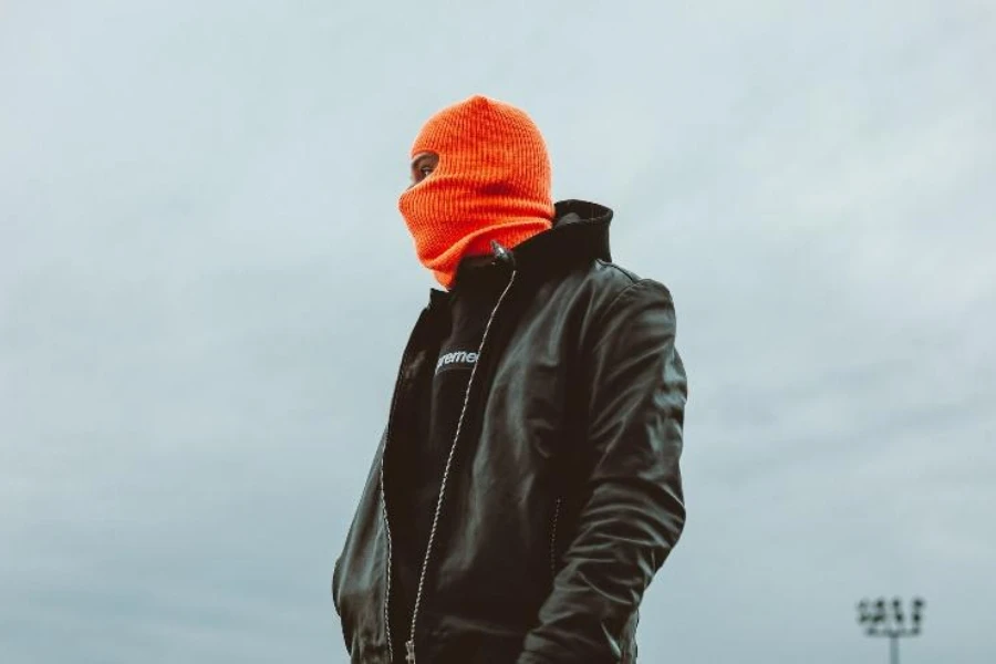 Homem com máscara balaclava laranja de um buraco