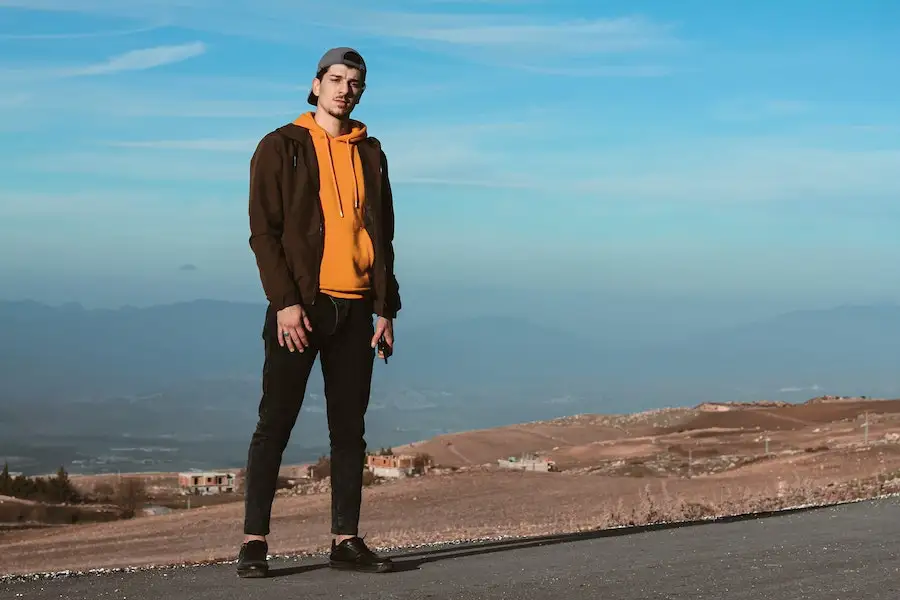 Homme portant une veste marron et un sweat à capuche orange