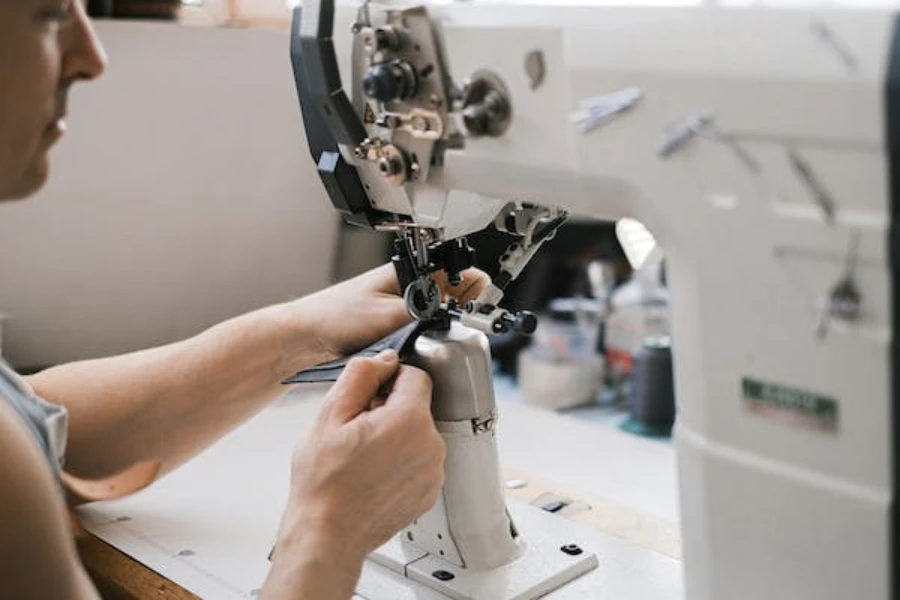 Hombre que usa una máquina post-cama para coser una billetera