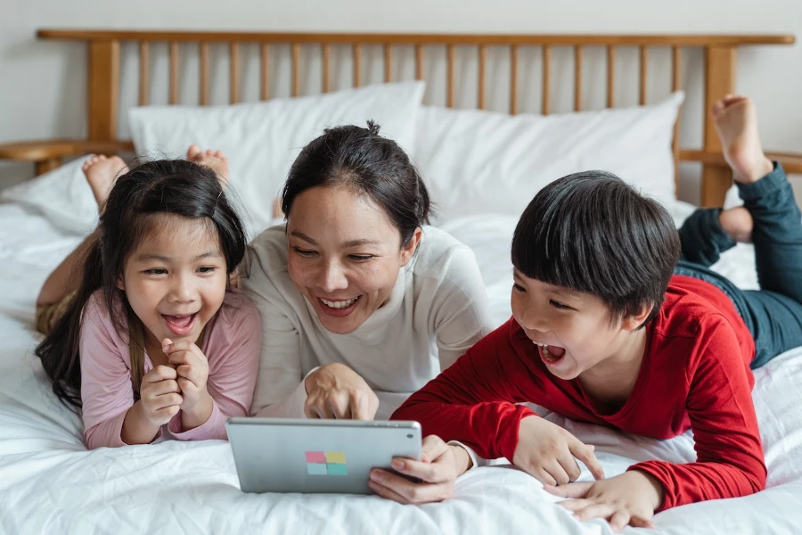 Mother pointing at tablet screen and children watching and laughing