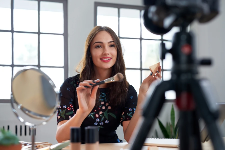 Pretty young vlogger recording makeup tutorial