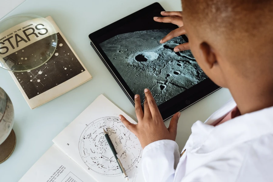 Student studying craters of moon on tablet at observatory