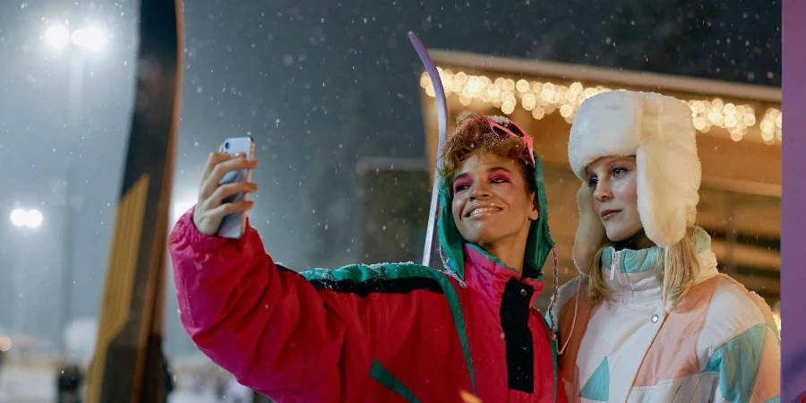 Two friends taking selfies while wearing winter jackets