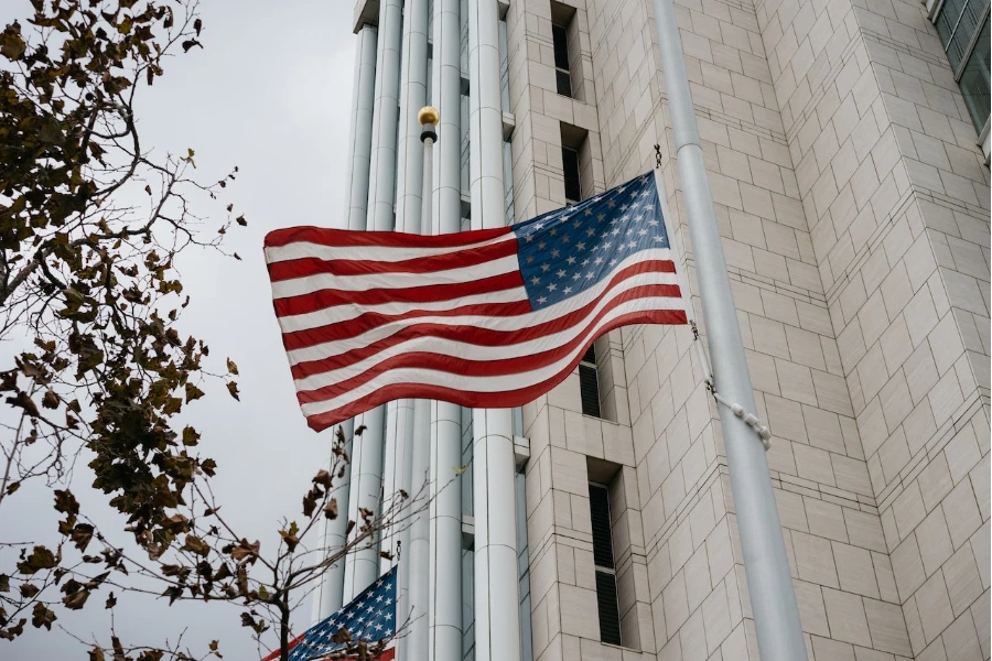 USA flag waving next to a large building