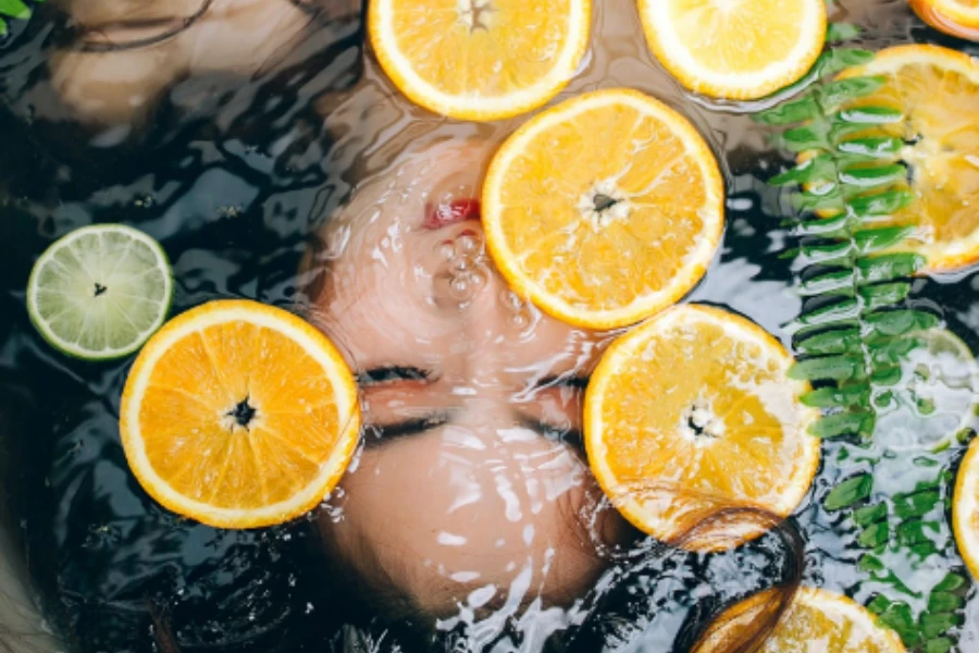 Woman and sliced citrus fruits in a bathtub