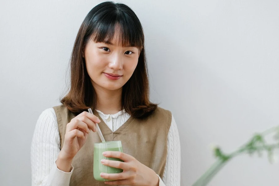 Woman holding matcha tea and wearing simple makeup