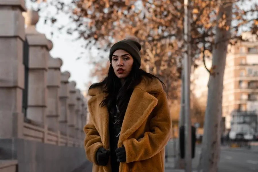 Woman in a brown mid-length weatherproof coat on the sidewalk