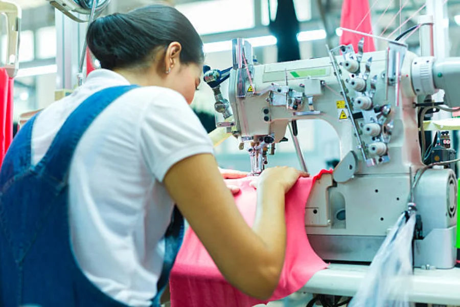 Frau näht ein Kleidungsstück an einer Industrienähmaschine