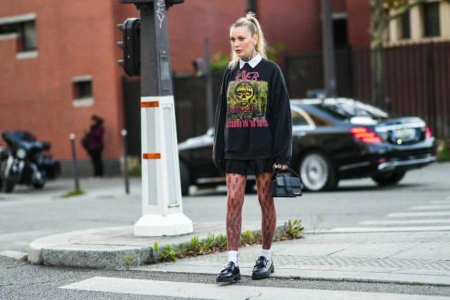 Woman wearing a black sweatshirt, fishnet stockings, and mini skirt