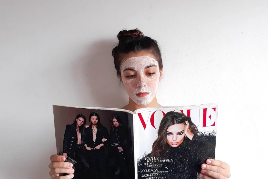 Femme portant un masque de soin et lisant un magazine