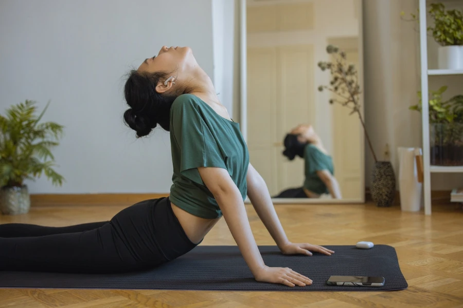 mujer, llevando, auriculares, mientras, hacer, yoga