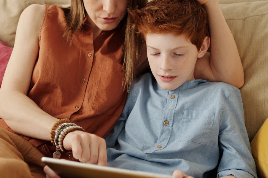 Femme avec son enfant lui apprenant à utiliser une tablette