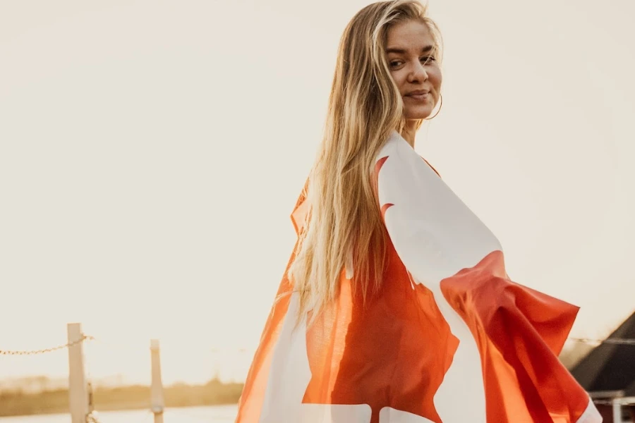 Mulher envolta com bandeira canadense sorrindo para a câmera