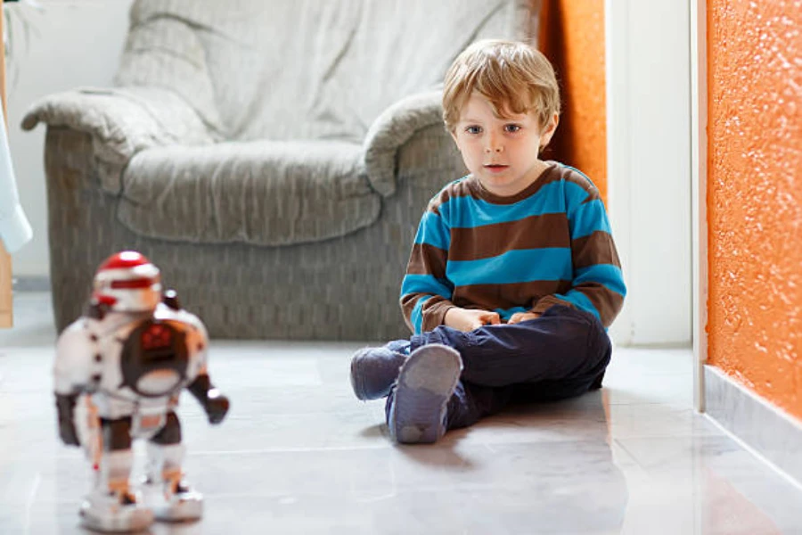 Young boy sitting on floor staring at a toy robot