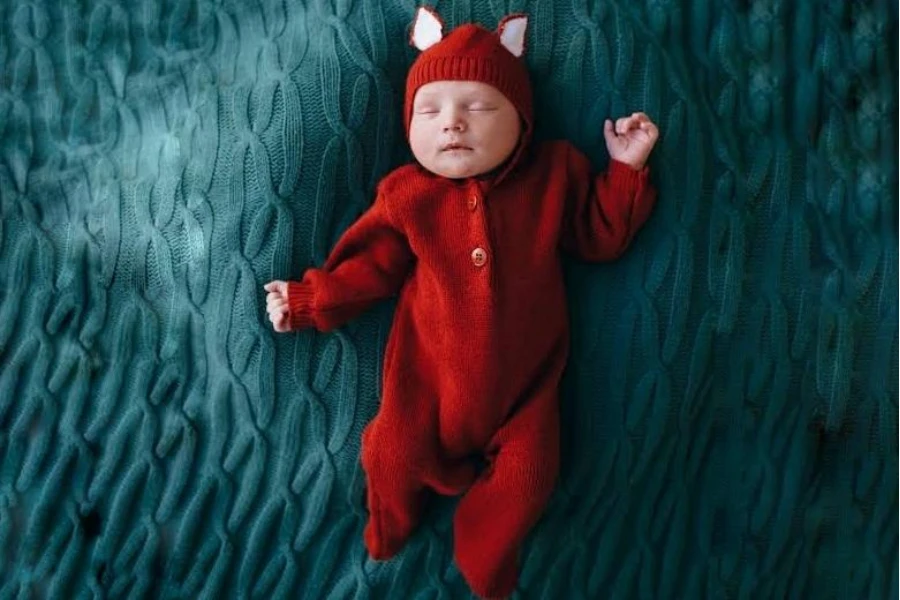 Un joli bébé en costume de barboteuse en tricot rouge