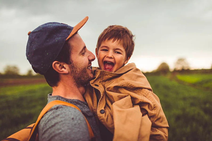 Un papa coiffé d'une casquette et tenant son enfant