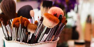 Assorted makeup brushes in a tan bucket