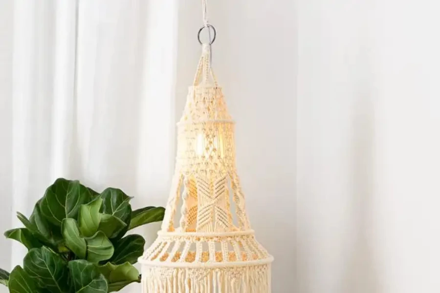 Beige macrame light hanging from ceiling with lightbulb on
