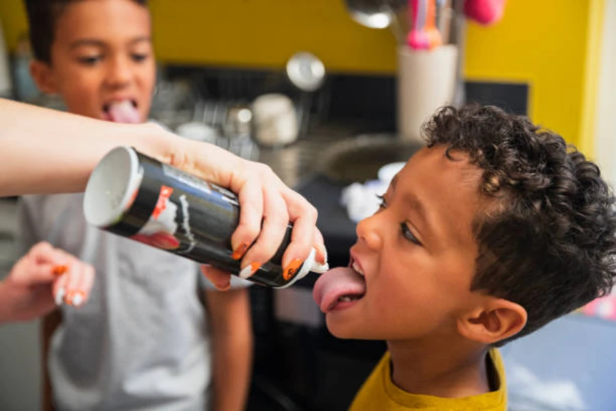 Niño con crema batida rociada directamente en su boca