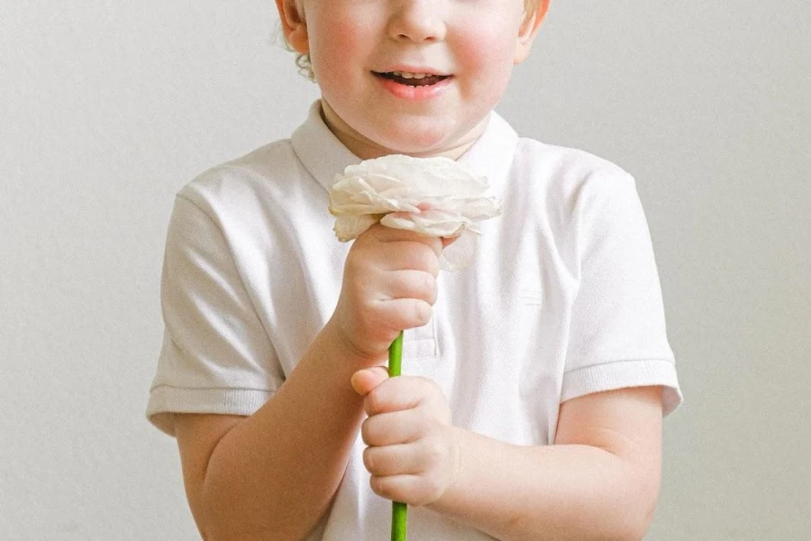 Boy in a white half-button tee holding a flower