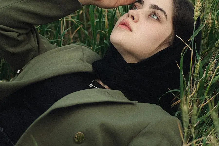 Lady lying on grass in a murky green jacket