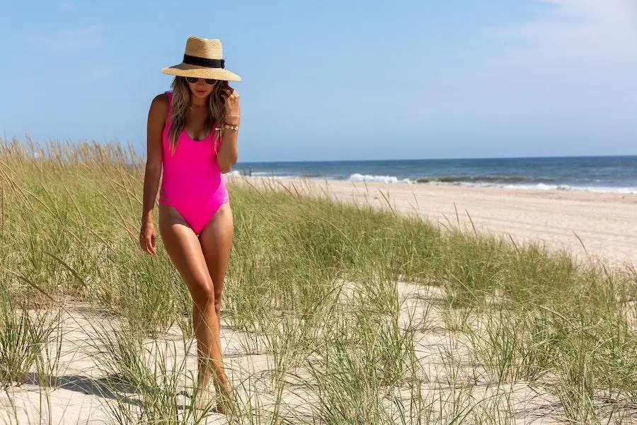 Lady on a beach wearing an ethereal pink swimsuit