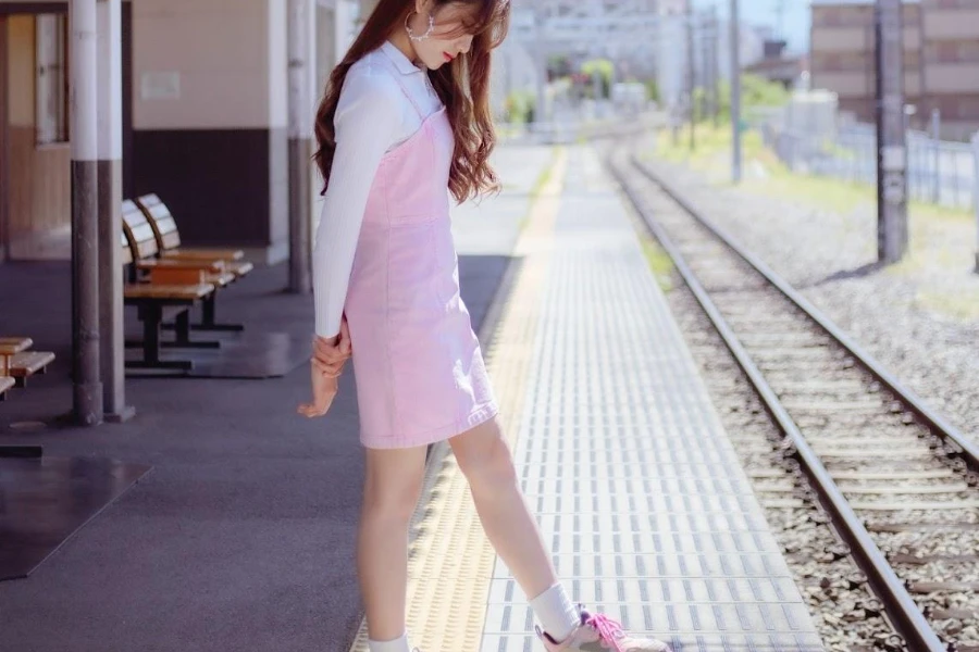 Lady wearing a pink pinafore and white long-sleeve top