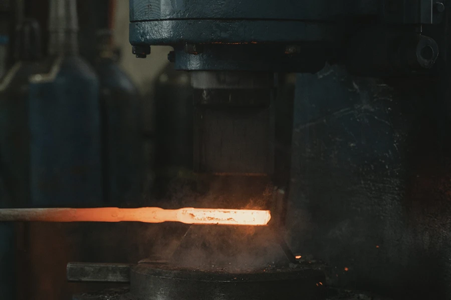 Machine forging a metal under high heat