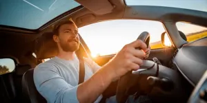 man driving his car at sunset