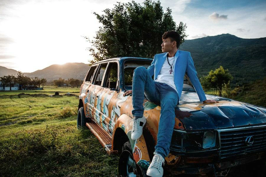 Homem posando em um carro enquanto usa um blazer azul