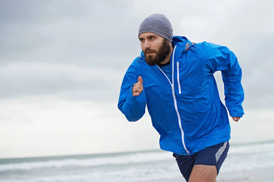 Man running on the beach wearing a gray running beanie