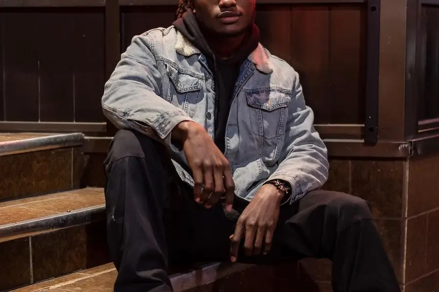 Man sitting on stairs rocking a denim utility jacket