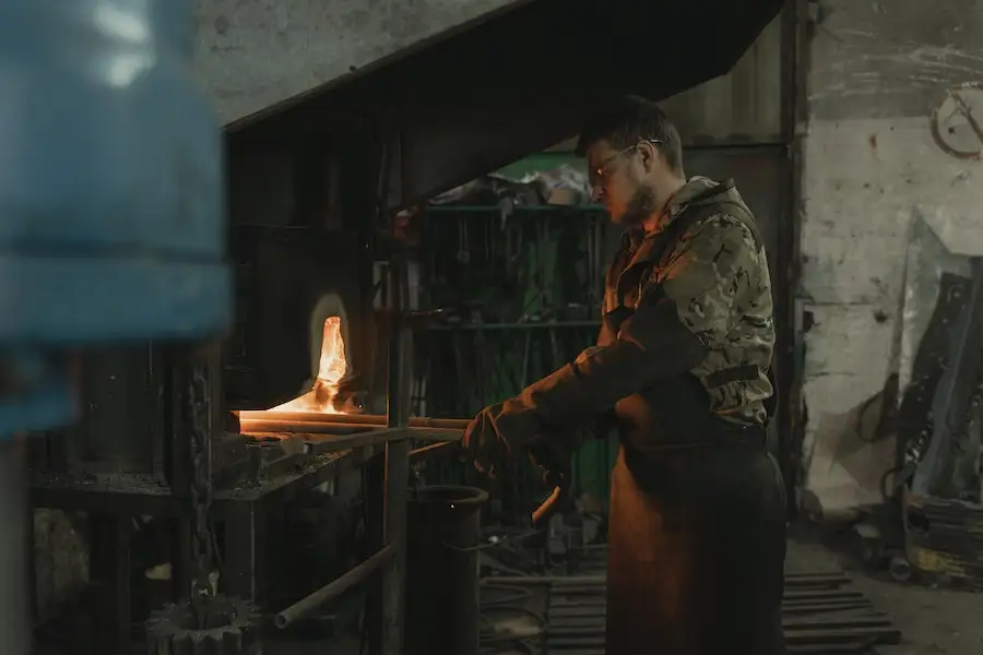 Man using metal forging machine to forge metal