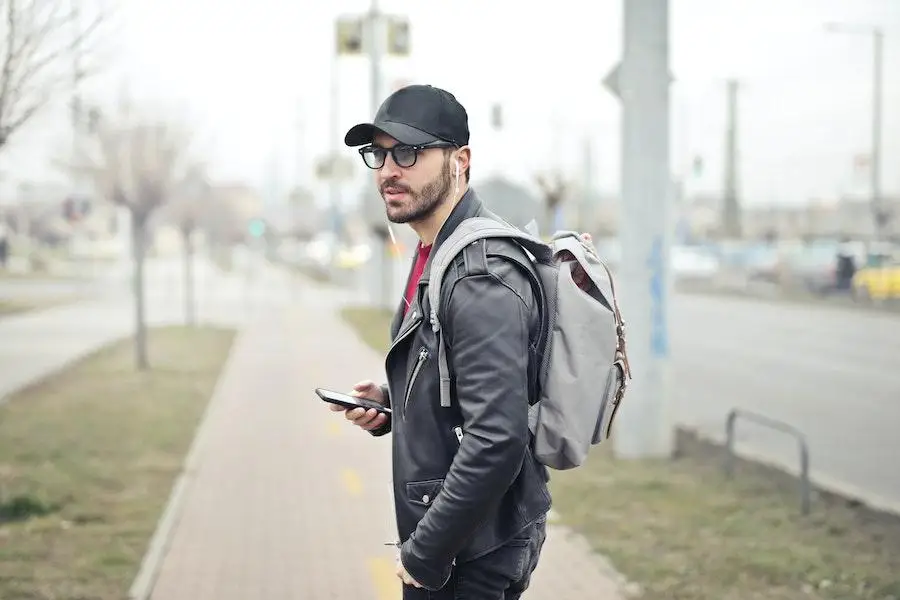 Homem vestindo um boné preto e jaqueta ao ar livre