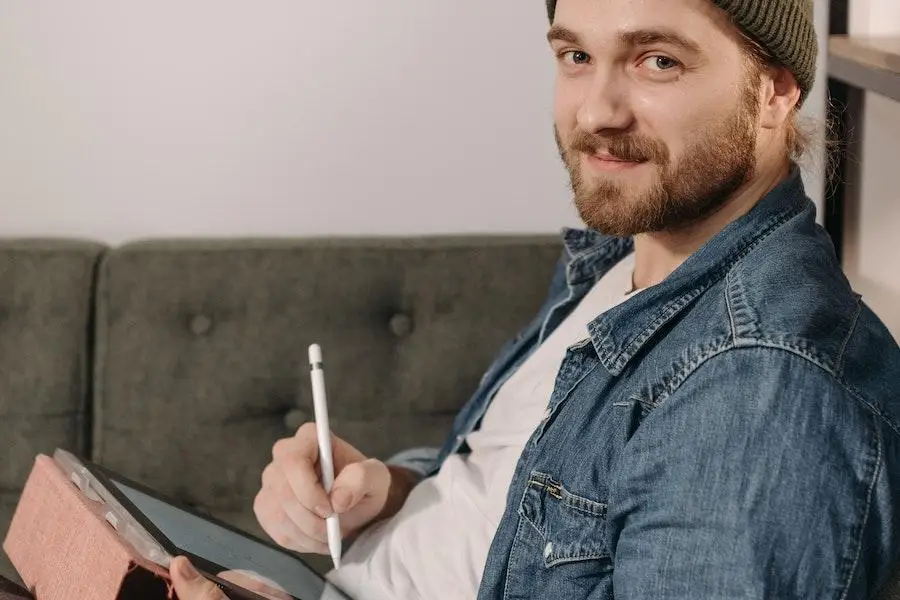 Uomo che indossa una camicia di jeans mentre tiene in mano un blocco note