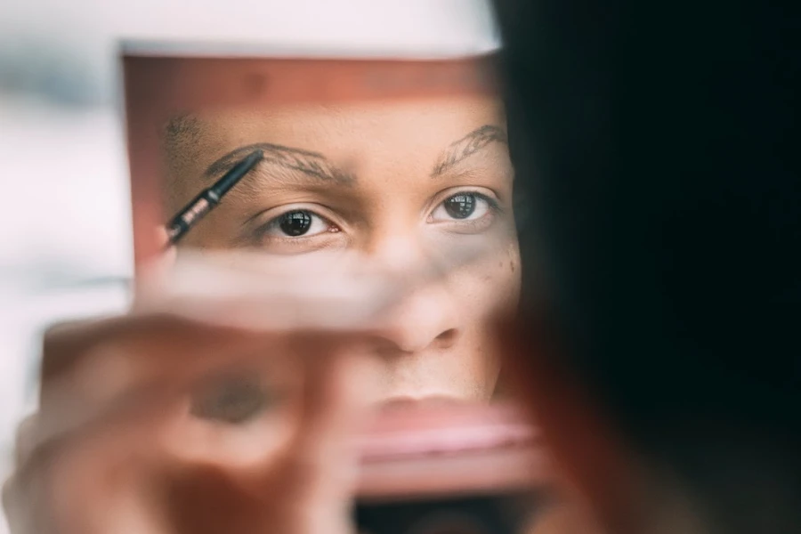 Person applying eyebrow pencil in a mirror