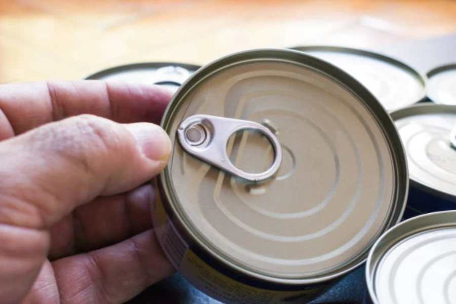 Person holding a small metal can used for fish