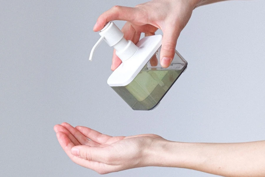 Person holding refillable soap dispenser above hand