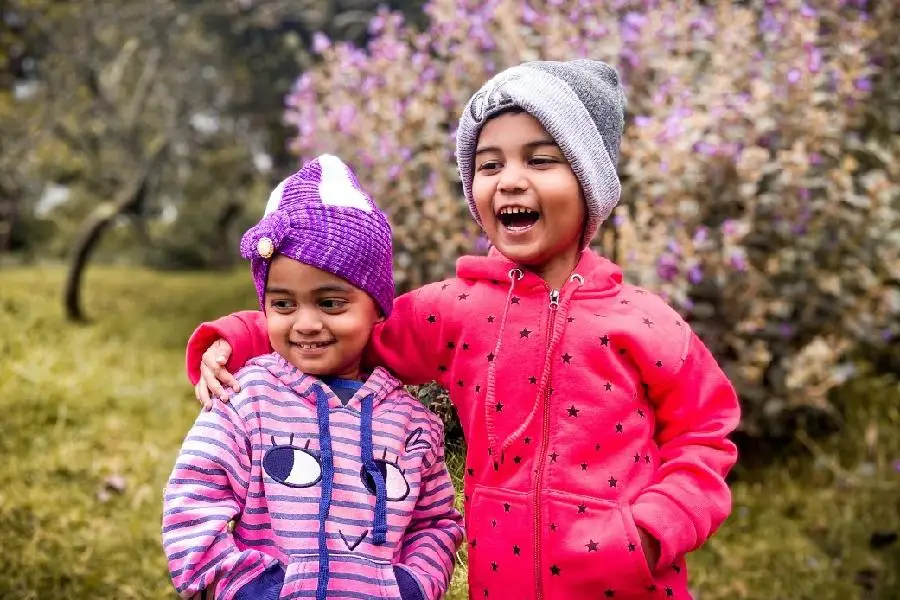 Due bambini in piedi vicino a un prato che indossano felpe a tre pezzi