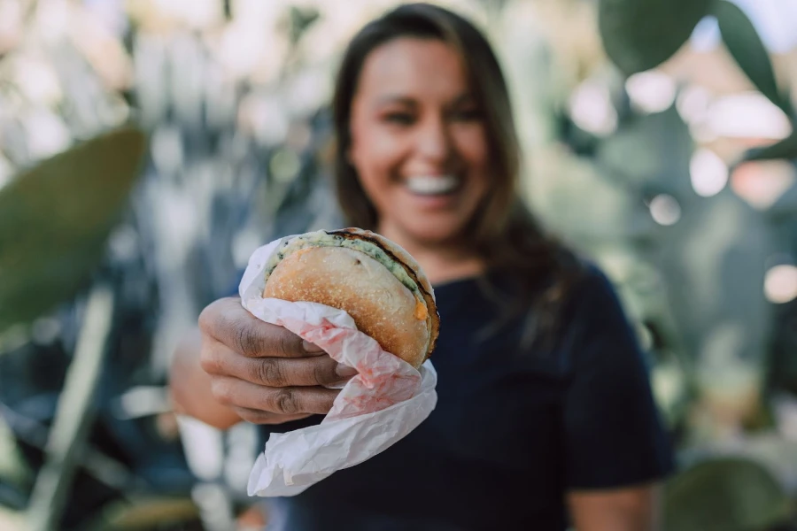 Mujer sosteniendo una hamburguesa en un envoltorio de comida