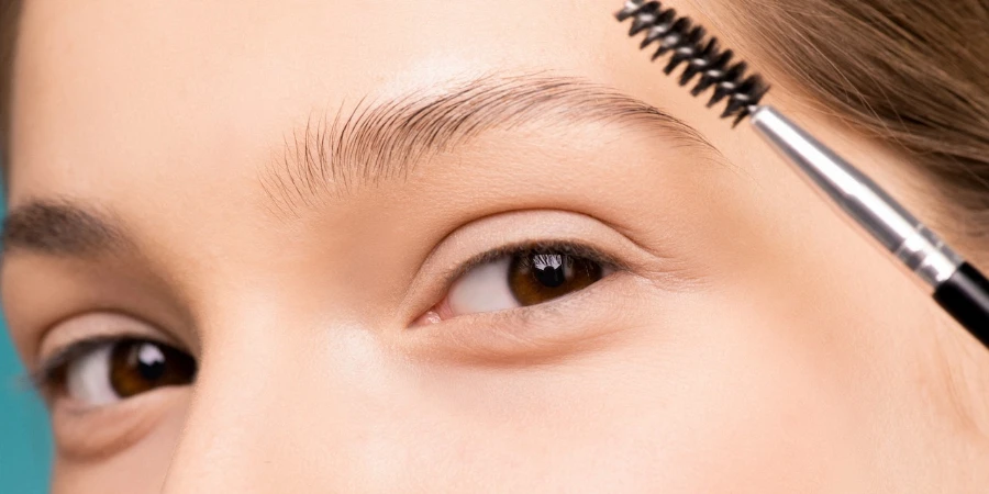 Woman holding brow brush to her eyebrow