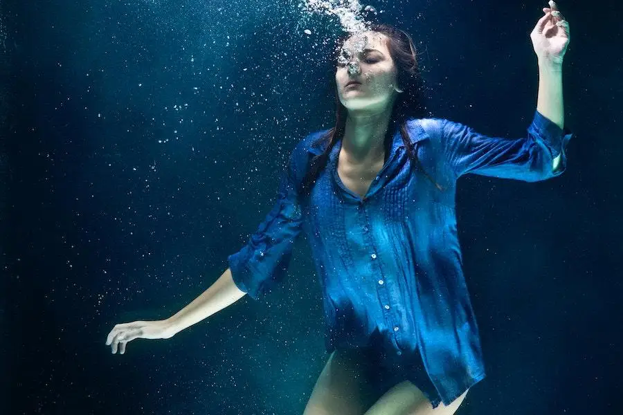 Frau in einem blauen Top posiert unter Wasser