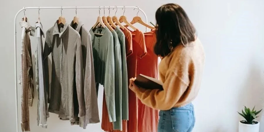 Woman in brown checking clothes on a hanging rack