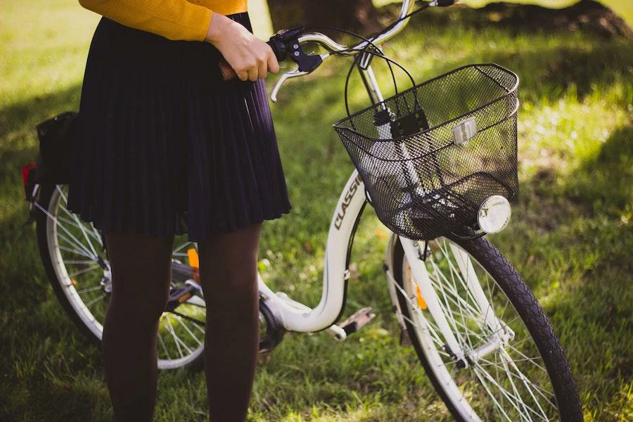 Woman wearing a pleated miniskirt holding a bike