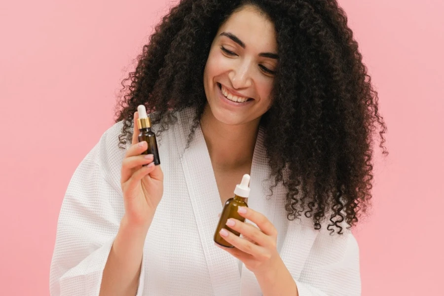 Femme aux cheveux bouclés tenant des produits cosmétiques